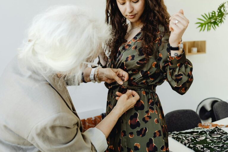 Senior woman assisting younger woman with dress fitting in tailoring session.